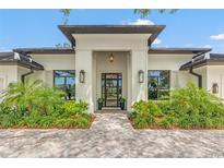 Modern home entrance with custom glass door, accent lighting and lush landscaping at 634 Poinsettia Rd, Belleair, FL 33756