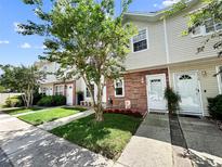 Charming townhomes with brick accents, manicured lawns, and sidewalk lined walkway to front door at 7508 Hollowell Dr, Tampa, FL 33615