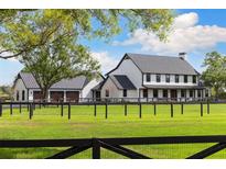 Stunning two-story farmhouse-style home with a three-car garage and lush green lawn at 11602 Innfields Dr, Odessa, FL 33556