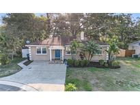 Charming home with a well-manicured lawn, mature trees, and a blue front door at 1513 Owen Dr, Clearwater, FL 33759