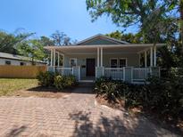 Charming bungalow featuring a covered front porch with columns, a brick walkway, and verdant landscaping at 1537 Palmetto St, Clearwater, FL 33755