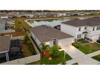 An aerial view shows this beautiful home with a screened-in pool, fenced yard and a picturesque pond in the neighborhood at 33581 Elm Hill Br, Wesley Chapel, FL 33545
