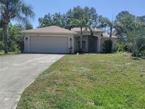 Single-story home featuring a two-car garage, a well-manicured lawn, and lush, mature landscaping at 3586 Culpepper Ter, North Port, FL 34286