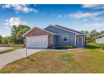 Charming single Gathering home features a brick facade, two-car garage, and well-maintained landscaping at 37434 Derbyshire Dr, Zephyrhills, FL 33542
