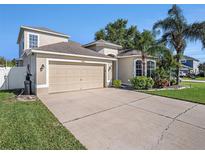 Charming home featuring a large garage, well-maintained lawn, and beautiful landscaping with palm trees at 4206 Morning Breeze Ct, Tampa, FL 33619