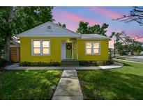 Charming yellow home featuring a cozy front porch and beautifully landscaped front yard with a sidewalk at 4462 2Nd S Ave, St Petersburg, FL 33711