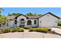 Charming home featuring white brick, arched windows, double-door entry, and lush landscaping at 4677 Del Sol Blvd, Sarasota, FL 34243