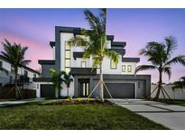 Modern two-story home boasts contemporary design, landscaping, and a multi-car garage at dusk at 7974 1St S Ave, St Petersburg, FL 33707