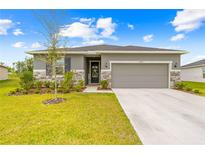 Charming single-Gathering home features stone accents, lush landscaping, and a welcoming two-car garage at 37587 Mackenzie Dr, Zephyrhills, FL 33540