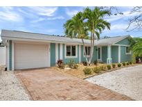 Charming home featuring a brick driveway, a one car garage and meticulous landscaping with tropical plants at 504 69Th St, Holmes Beach, FL 34217