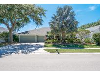 Charming single-story home with a three-car garage, lush landscaping, and a well-manicured lawn at 5269 Karlsburg Pl, Palm Harbor, FL 34685