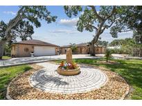 Charming home with a circular flower bed in the front yard and mature trees providing shade at 6732 Udell Ln, Hudson, FL 34667