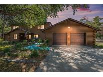 Charming log-cabin-style home with a two-car garage and well-manicured landscaping at 7157 Quail Hollow Blvd, Wesley Chapel, FL 33544