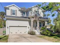 Charming two-story home features a neutral color palette, inviting front porch, and attached two-car garage at 7501 S Morton St, Tampa, FL 33616