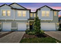 Charming townhome showcasing two-story facade, modern windows, well-kept landscaping, and private garages at 8953 Gallantree Pl, Land O Lakes, FL 34637