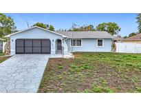 Charming light blue single Gathering home featuring an attached garage and landscaped front yard at 12083 Rockford St, Spring Hill, FL 34608
