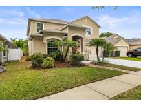 Inviting two-story home with a well-manicured lawn, lush landscaping, and a charming brick-lined walkway at 18243 Cypress Bay Pkwy, Land O Lakes, FL 34638