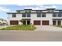 Modern townhouse exteriors with white siding, dark trim, and brown garage doors at 187 145Th E Ave # 3, Madeira Beach, FL 33708