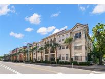 Exterior view of a multi-story condo building with palm trees lining the street at 2410 W Azeele St # 228, Tampa, FL 33609