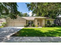 Charming single-story home with a well-manicured lawn, mature trees, and a three-car garage at 2803 Bent Leaf Dr, Valrico, FL 33594