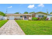 Charming single-story home featuring a well-maintained lawn and brick-paved walkway, enhancing curb appeal at 6345 Dartmouth N Ave, St Petersburg, FL 33710