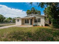 Charming home featuring a well-manicured lawn, brick walkway, neutral paint, and mature landscaping at 1923 W State St, Tampa, FL 33606