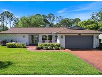 Charming single-story home featuring a brick driveway, lush lawn, and well-maintained landscaping at 2673 Clubhouse S Dr, Clearwater, FL 33761