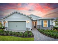 Charming single-Gathering home with a well-manicured lawn, stone accents, and a two-car garage under a colorful sunset sky at 29152 Coral Harbour Dr, Englewood, FL 34223