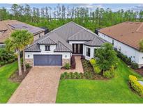 Beautiful one-story home featuring a gray tile roof, brick driveway, manicured lawn, and a two-car garage at 29356 Ginnetto Dr, Wesley Chapel, FL 33543