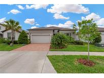 Charming single-story home with brick driveway, lush landscaping, and a two-car garage at 5128 Dockyard Pl, Land O Lakes, FL 34638