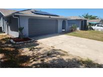 Charming single-story home featuring a two-car garage, solar panels, and a well-maintained lawn at 11715 Salmon Dr, Port Richey, FL 34668