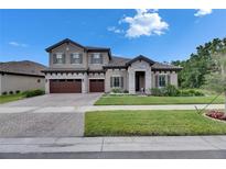 Charming two-story home with gray stucco, tile roof, stone accents, and a manicured lawn at 14421 Swiss Bridge Dr, Lithia, FL 33547