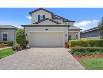 Two-story home featuring a paved driveway leading to an attached two-car garage and landscaped yard at 1949 Parterre Ave, Lutz, FL 33558