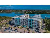 Scenic aerial view of waterfront condos with a parking lot, mature landscaping, and beautiful water views at 19531 Gulf Blvd # 604, Indian Shores, FL 33785