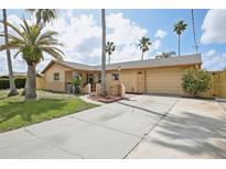 Inviting single-story home features a well-manicured lawn, long driveway and attached garage at 5616 Riddle Rd, Holiday, FL 34690
