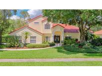 Charming two-story home with lush landscaping, red tile roof, and arched entryway at 8907 Magnolia Chase Cirs, Tampa, FL 33647