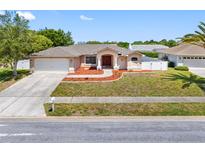 Charming single Gathering home featuring a well-manicured lawn and a two-car garage at 1061 Archway Dr, Spring Hill, FL 34608