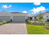 Charming single-story home featuring a brick driveway, two-car garage, and beautifully landscaped front yard with green grass at 27152 Capri Shores Cir, Englewood, FL 34223