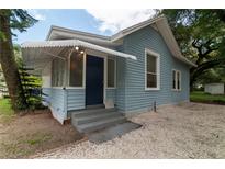 Charming light blue home with white trim, awning, well-maintained yard, and inviting entryway at 3409 N 10Th St, Tampa, FL 33605