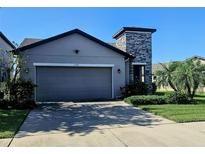 Charming home with a two-car garage, well-kept lawn and stone column feature at 5154 Brickwood Rise Dr, Wimauma, FL 33598