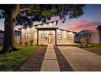 Beautifully renovated home featuring a modern exterior, manicured lawn, and well-lit walkway, with a striking tree to the side at 1514 55Th N Ave, St Petersburg, FL 33703