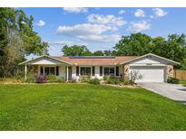 Charming single-story home with a well-manicured lawn, stone accents, and a welcoming covered porch at 17605 Simmons Rd, Lutz, FL 33548