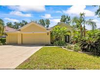 Inviting single-story home featuring a three-car garage and lush tropical landscaping at 2613 Bonterra Blvd, Valrico, FL 33594