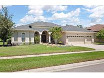 Stunning single-story home with a well-manicured lawn, arched entryway, and three-car garage at 3009 Sheehan Dr, Land O Lakes, FL 34638