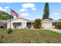 Charming single-story home with an American flag, lush green lawn, and attached garage at 4209 Stratfield Dr, New Port Richey, FL 34652