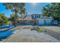 Charming brick home with lush landscaping, a two-car garage and a serene walkway at 508 N Mayo St, Crystal Beach, FL 34681
