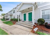 Charming townhouse with green front doors, landscaped bushes, and a concrete walkway at 5503 67Th N Ave # 18, Pinellas Park, FL 33781