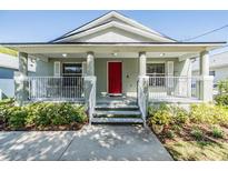 Charming home with a covered front porch, white railing, and a bright red front door at 7508 S Mascotte St, Tampa, FL 33616