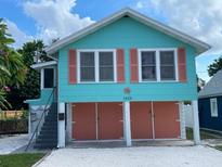 Charming raised cottage home with turquoise siding, coral shutters, and a two-car garage at 1626 27Th N Ave, St Petersburg, FL 33713