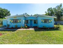 Charming home featuring a cheerful blue exterior, yellow shutter accents, and a well-maintained lawn at 17111 Mockingbird Ln, Lutz, FL 33548
